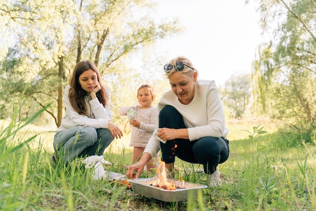 Family with small child teen and grandmother doing bbq on the nature Single use barbeque grill