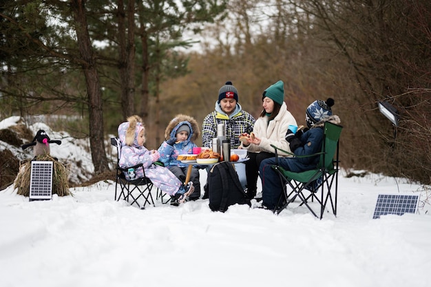 Family with three children in winter forest spending time together on a picnic