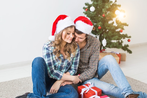 Family, x-mas, winter holidays and people concept - happy couple hugging near christmas tree at home.