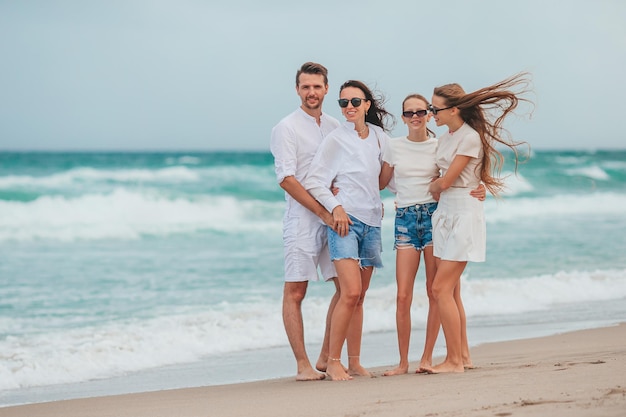 Family of young parent and two kids smiling and enjoy time together on the beach vacation