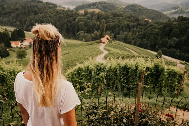 Photo famous heart shaped road at vineyards spicnik in slovenia woman standing at the edge and looking at wonderful grape landscape scenery and green hills