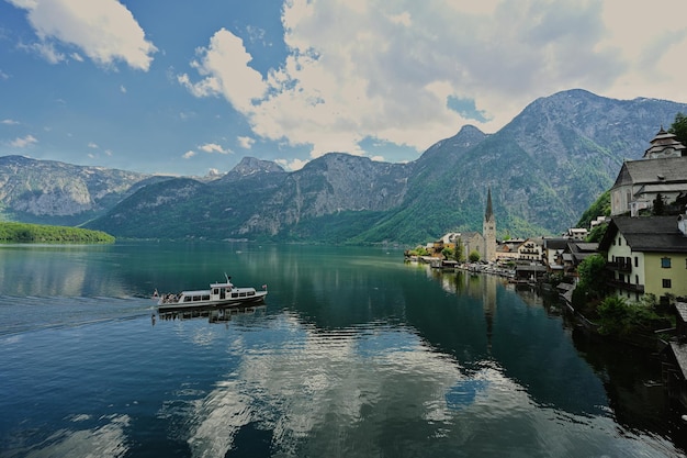 Famous old town Hallstatt and alpine deep blue lake with tourist ship Austria