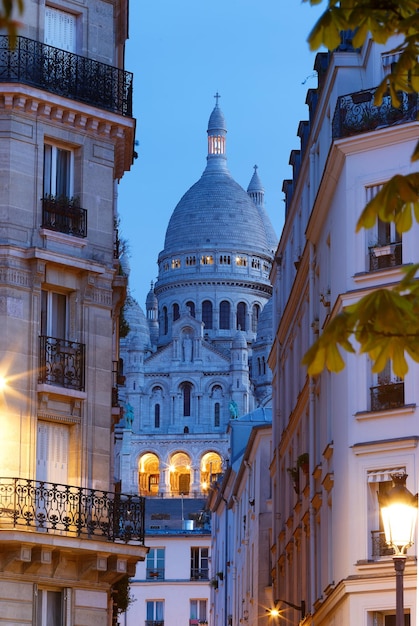 The famous sacrecoeur basilica between haussmann buildings in paris at night