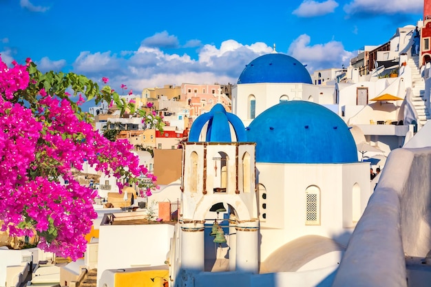 Famous Santorini view Three blue domes and traditional white houses with bougainvillea flowers Oia village Santorini island Greece