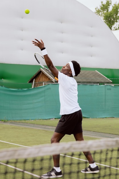 Famous tennis player of african appearance trains on tennis court he throws up tennis ball