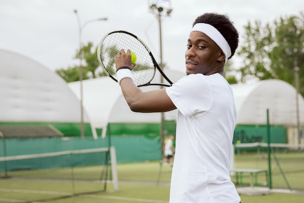 Famous tennis player of african appearance trains on tennis court and poses for photo