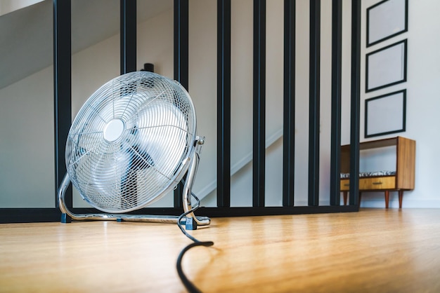 A fan on the floor is sitting on a wooden floor Air conditioning hot summer