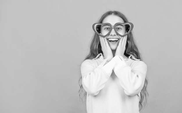 Fancy party look happy funny kid in glamour eyeglasses on blue background