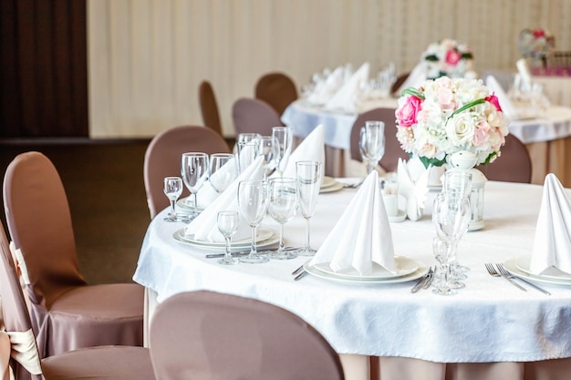 Fancy table set for dinner with flower composition in restaurant luxury interior background wedding