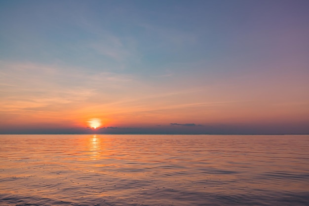 Fantastic closeup view of calm sea water waves with orange sunrise sunset sunlight. Tropical island