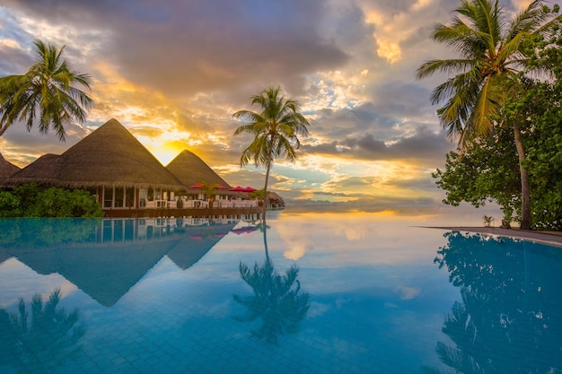 Fantastic poolside, sunset sky palm trees reflection. Luxury tropical beach landscape infinity pool