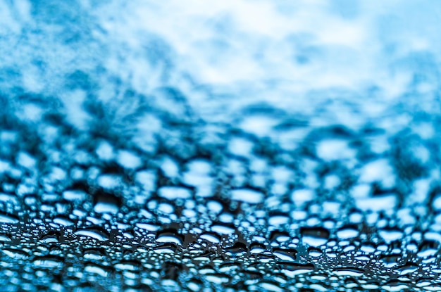 Fantastic view of clear big and small raindrops on a glass on blue background Realistic pure water droplets condensed for creative design Macro shot