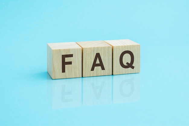 Faq an abbreviation of wooden blocks with letters on a blue background Reflection of the caption on the mirrored surface of the table Selective focus faq short for frequency asked qquestions