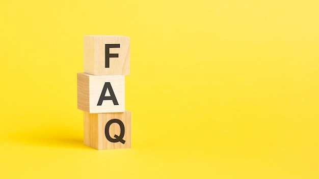 FAQ text on wooden cubes on yellow background