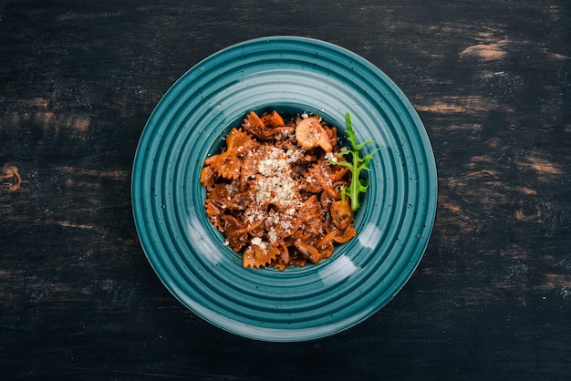 Farfalle pasta with mushrooms. On a wooden background. Italian cuisine. Top view. Copy space.