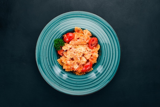 Farfalle pasta with tomatoes and parmesan cheese Italian cuisine On a wooden background Top view Copy space