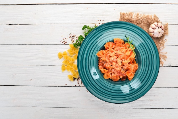 Farfalle pasta with tomatoes and parmesan cheese On a wooden background Italian cuisine Top view Copy space