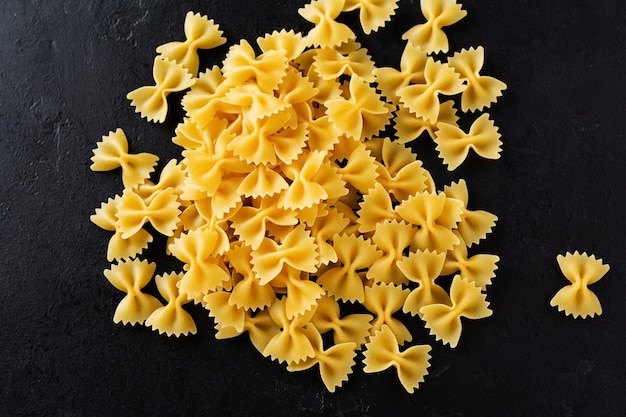 Farfalle raw pasta on black concrete table. Cooking concept. Top view with copy space.