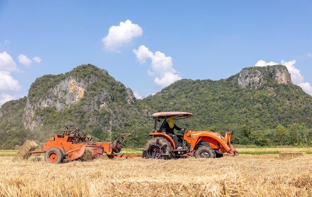 On a farm in Ratchaburi Thailand farmers use agricultural machine to compress and bundle rice straw