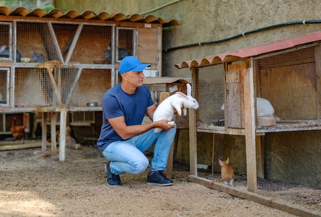 Farmer caucasian rural portrait in countryside with white rabbit in his arms outdoors outside