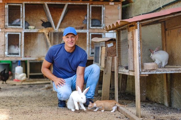 Farmer caucasian rural portrait in countryside with white rabbit in his arms outdoors outside