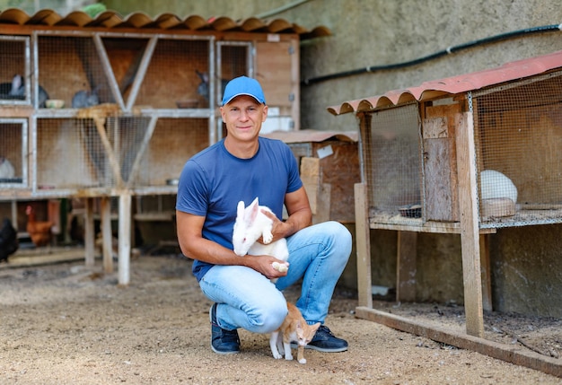 Farmer caucasian rural portrait in countryside with white rabbit in his arms outdoors outside