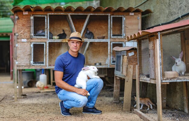 Farmer caucasian rural portrait in countryside with white rabbit in his arms outdoors outside