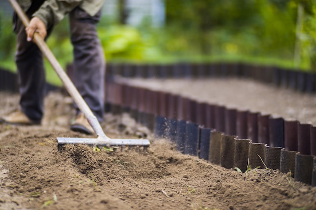 Farmer cultivating land in the garden with hand tools Soil loosening Gardening concept Agricultural work on the plantation