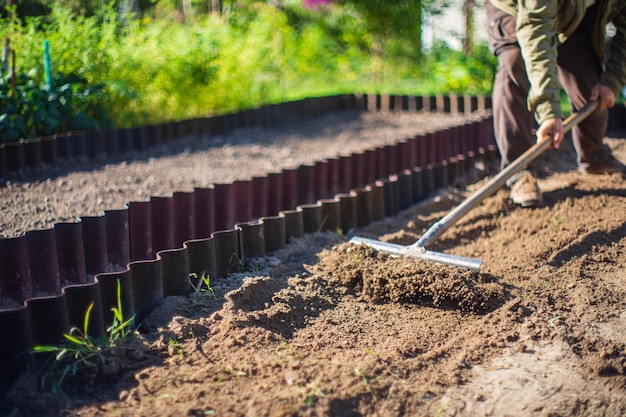 Farmer cultivating land in the garden with hand tools Soil loosening Gardening concept Agricultural work on the plantation