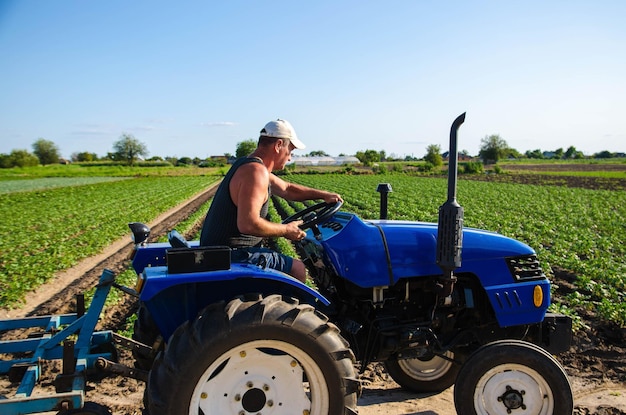 The farmer drives a tractor on the farm Agroindustry and agribusiness A man driver works in the field Farm machinery Agricultural business Plowing and loosening ground