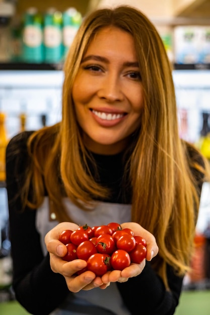 Farmer female hands in apron holding heap fresh ripe red cherry tomatoes in heart shape closeup