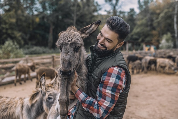 A farmer holding a donkey and smiling