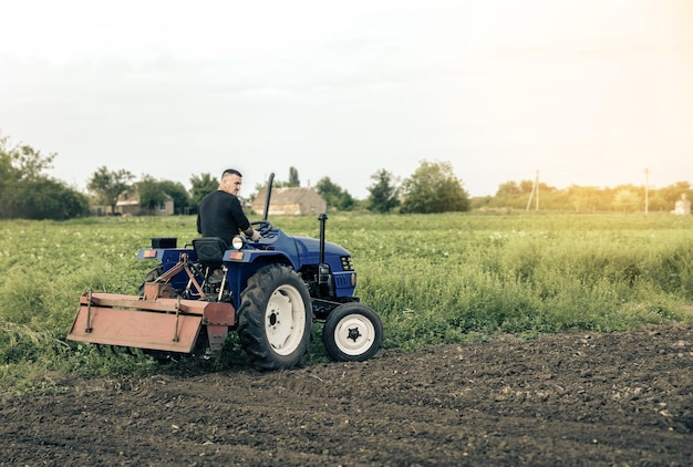 A farmer is driving a tractor across the field Mill grinding machine for soil Land cultivation Recruiting and hiring seasonal worker for work Farming agriculture Land improvement mitigation