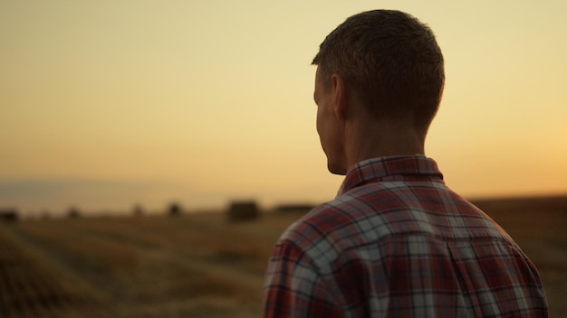 Farmer looking machinery at gold sunset farmland Agricultural business concept