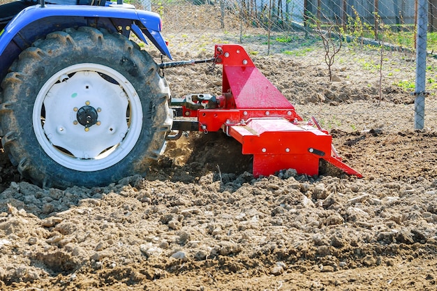 Farmer plows the field. Small tractor with a plow in the field. Cultivation.