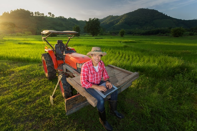 Farmer recorded growth of productivity sitting on a tractor in the background a rice paddy