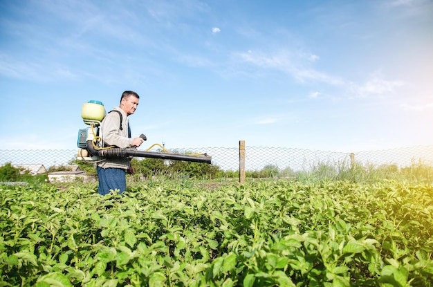 A farmer with a pesticide sprayer machine walks across the field Protection of plants from insects and fungal infections Chemical industry in farming agriculture Resistance of the crop to pests