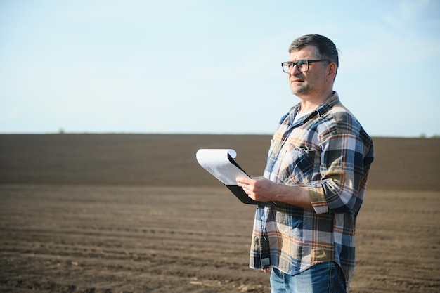 A farmer works in a field sown in spring An agronomist walks the earth assessing a plowed field in autumn Agriculture Smart farming technologies