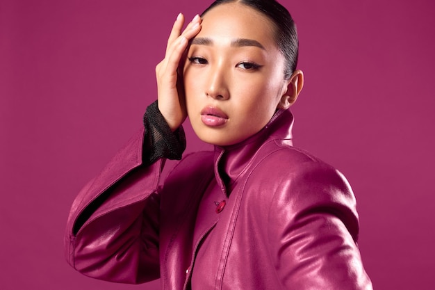 Photo fashion asian brunette in purple leather jacket and black shirt posing against purple background