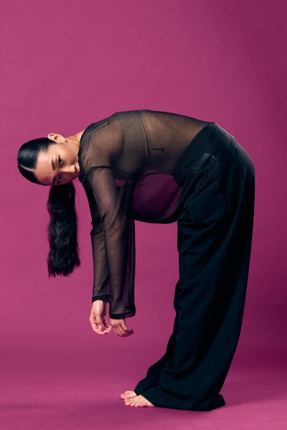 Photo fashion asian woman in sheer top bending over with hands on knees head tilted on purple background