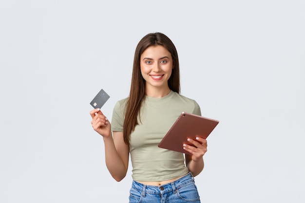 Fashion and beauty, lifestyle and shopping concept. Smiling good-looking female customer, girl making online order with credit card and digital tablet, shop in internet, white background