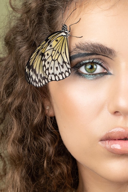 Fashion beauty model with butterfly on face and color professional makeup SPA wellness makeup and skincare concept