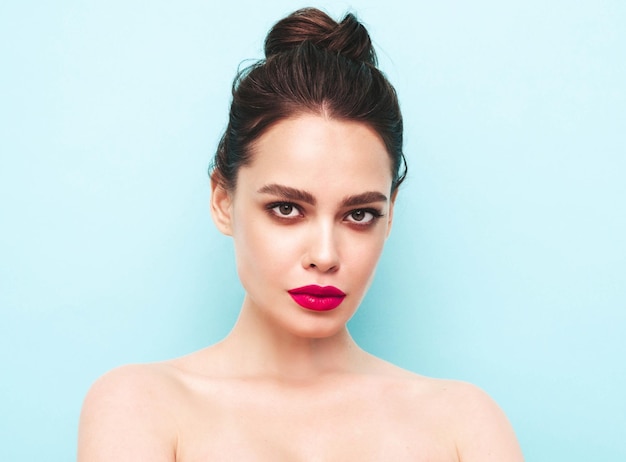 Fashion beauty portrait of young brunette woman with evening stylish makeup and perfect clean skin Sexy model with hair in a bun posing in studio With pink bright natural lips