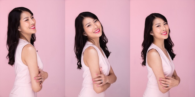 Fashion Beauty Woman has long black hair looks at camera and express feeling happy. Portrait of Asian girl wear pink dress over pink tone background