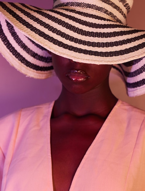 Fashion beauty and woman in neon light UV and purple studio background wearing a sun hat Style makeup and African American female model with dark skin aesthetic creativity color and design