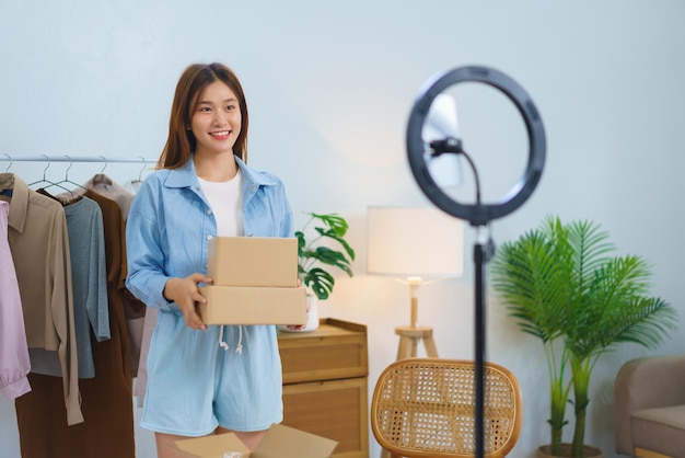 Fashion blogger concept Young Asian women hold parcel boxes while streaming video selling clothes