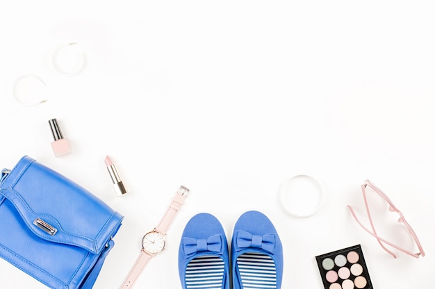 Fashion blogger workspace flat lay with navy flats, cosmetics, purse, sunglasses.