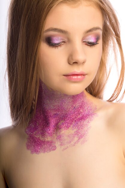 Fashion blonde model with art makeup posing at studio over a white background