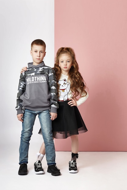 Fashion boy and girl in stylish clothes on colored wall. Autumn bright clothes on children, a child posing on a colored purple pink wall.