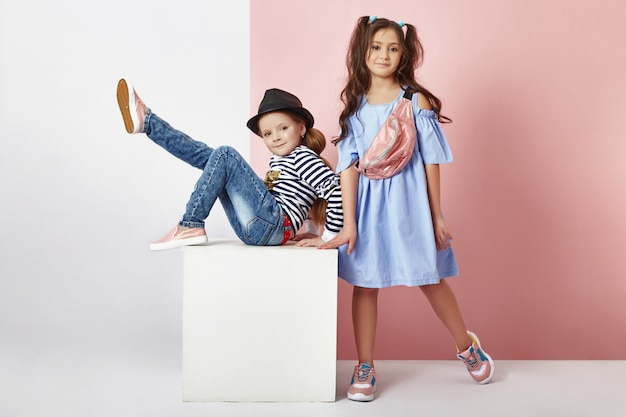 Fashion boy and girl in stylish clothes on colored wall b